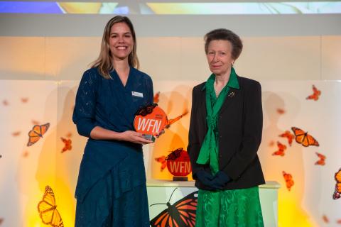 Photo of Smithsonian scientist Fernanda Abra smiling and holding an award. Beside her stands British royal Princess Anne, who presented her with the award.