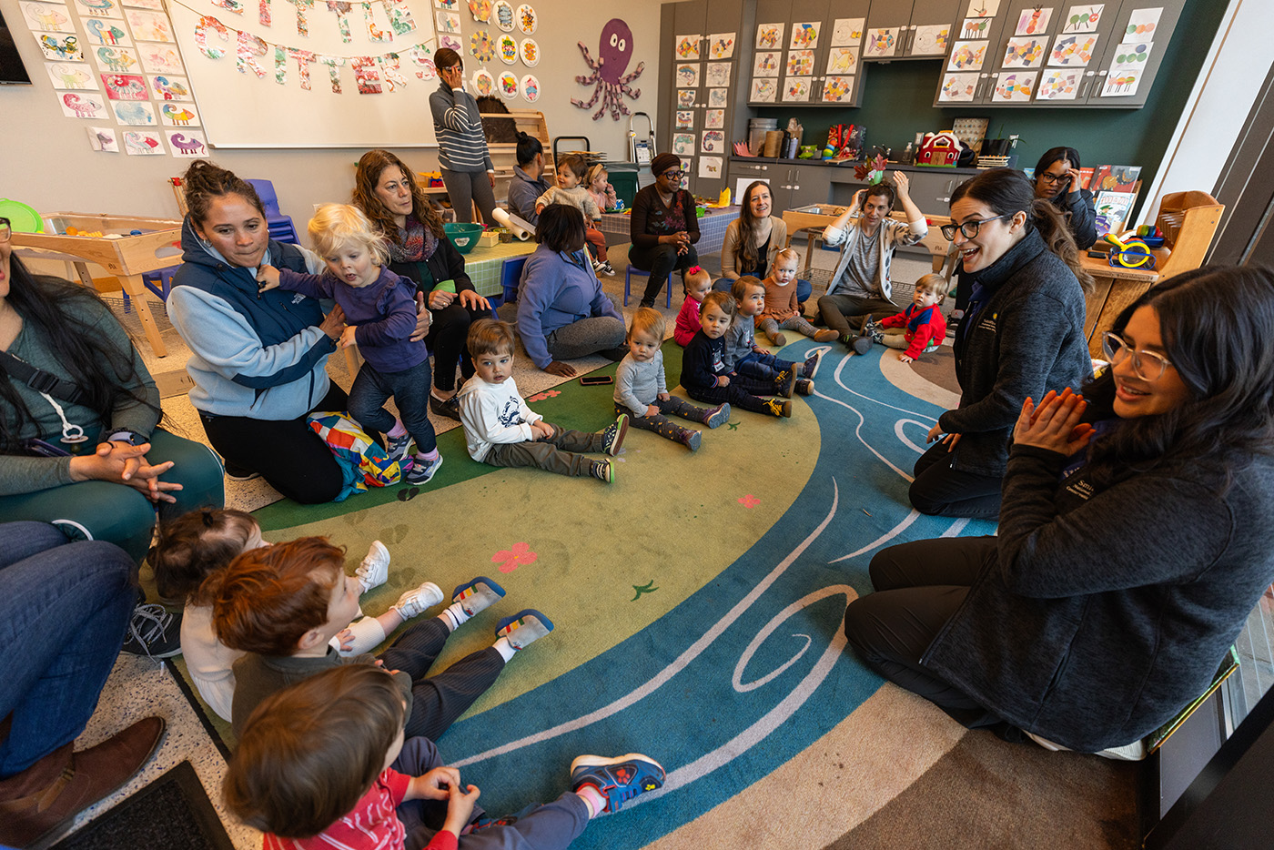 Young children and their caregivers sit in a circle for storytime.