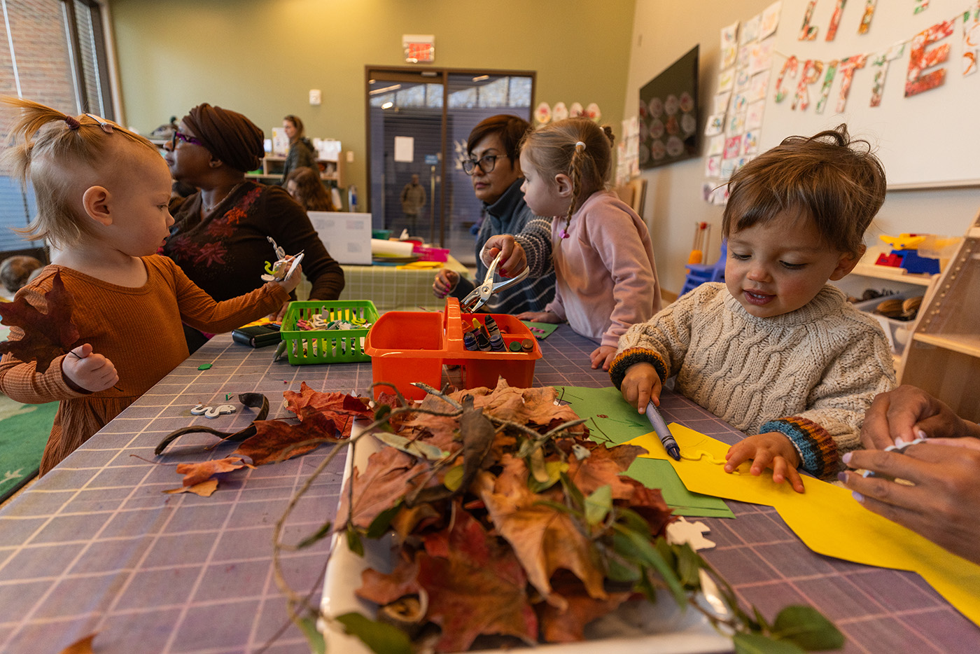 Children playing with fallen leaves at a craft table