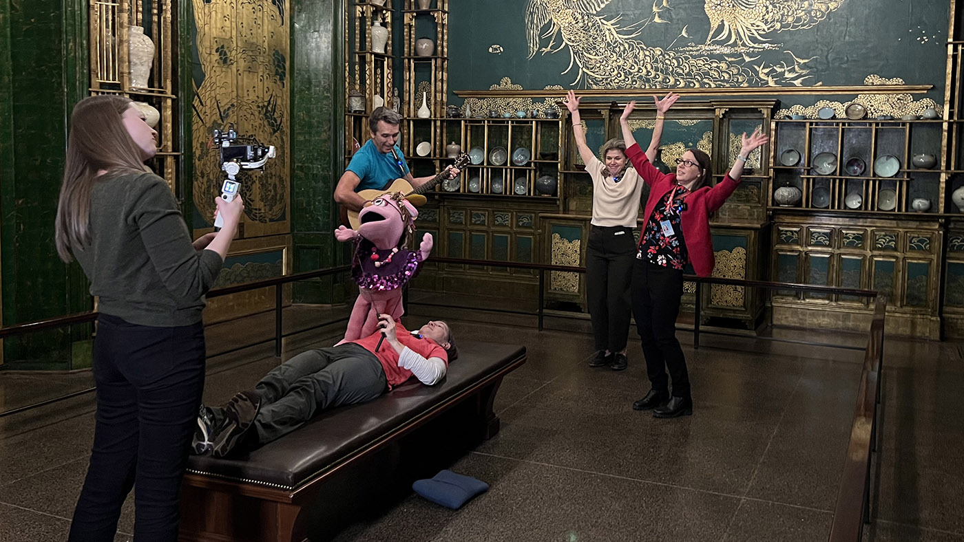 A crew of museum professionals and educators films inside an ornately decorated room.