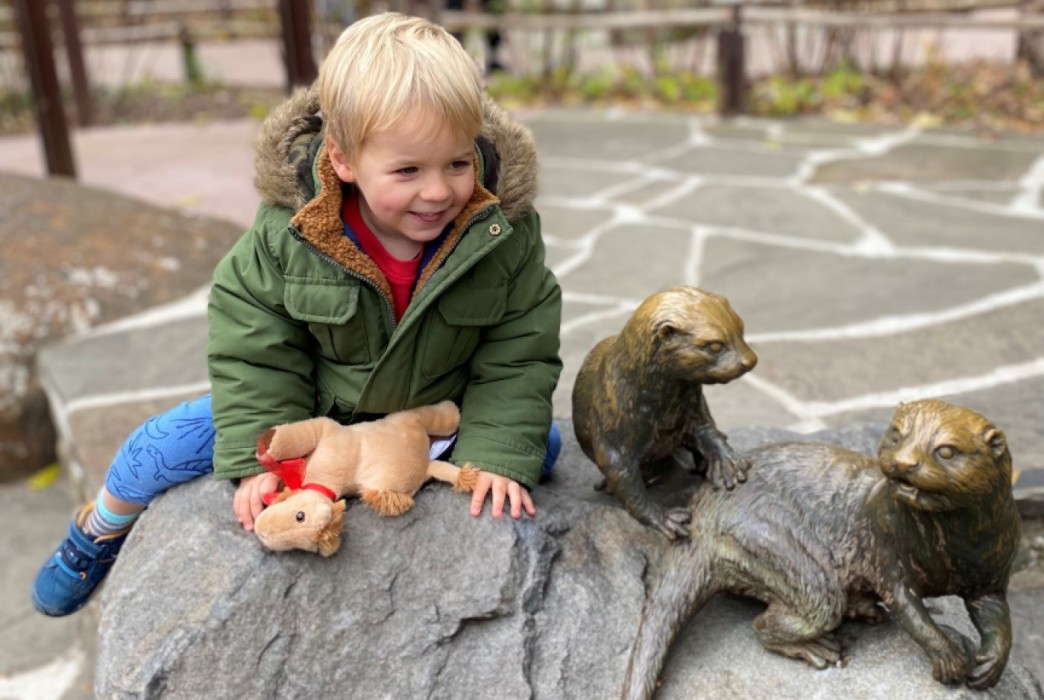 Child plays on Asian small clawed otter statue