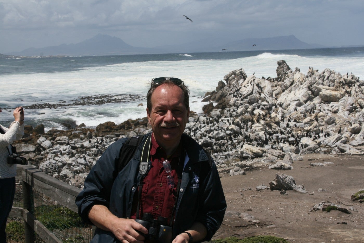 Steve Sarro poses in front of a colony of African Penguins in 2014 in South Africa