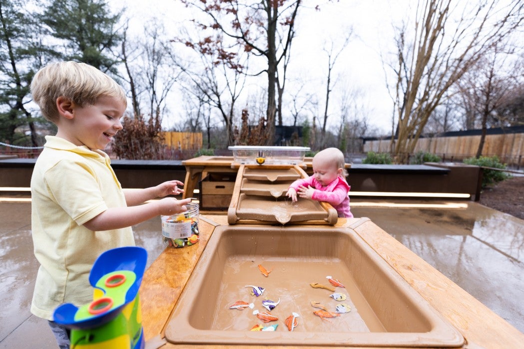 Two children play in a water table