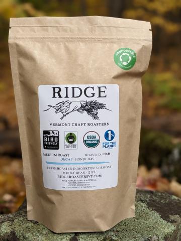 a coffee bag with an illustration of a bird perching on a pine branch
