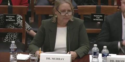 Suzan Murray sits at a table with a piece of paper in her hand