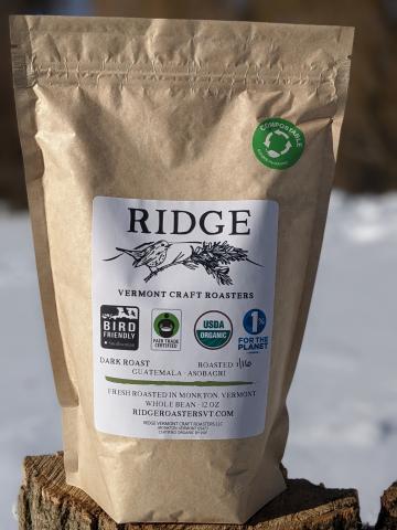 a coffee bag with an image of a bird perched on a pine branch