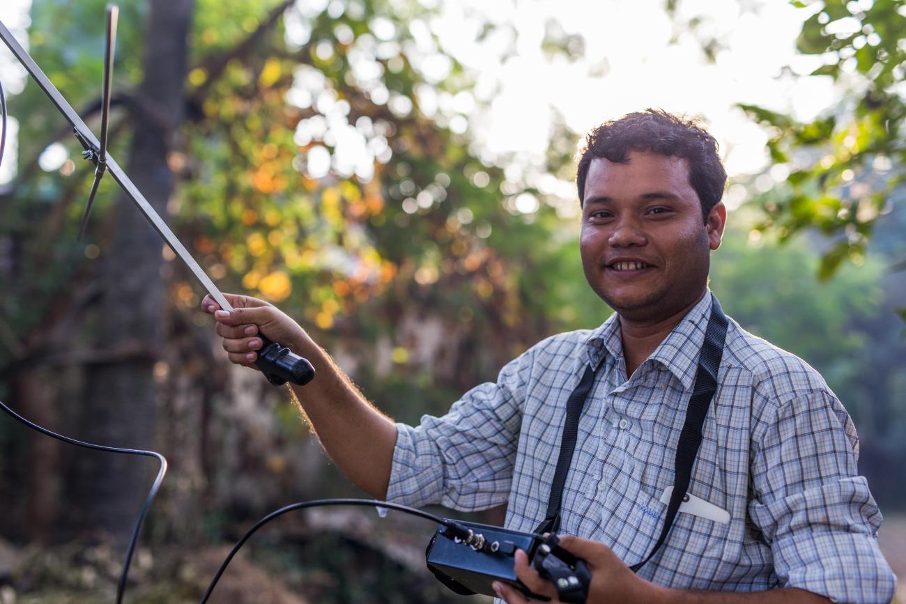 Scientist Kyaw Yan Naing Tun holds a transceiver toward the sky in Myanmar