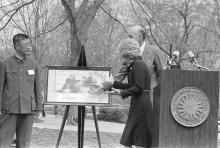 First Lady Patricia Nixon stands near a podium and looks at a photo of giant pandas April 20, 1972, for the official welcome ceremony for giant pandas Ling Ling and Hsing Hsing