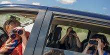 a group of people with binoculars look out the window of a car