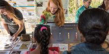 A researcher at the Smithsonian Conservation Biology Institute points to a scientific poster and talks to students about her work