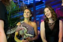 Two women talking to an interpreter holding a large snake at the Smithsonian's National Zoo's Monkey Business Gala