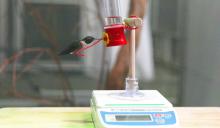 Ruby-throated hummingbird Spot sits on a feeder atop a scale. 