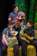 Three "Erth's Dinos Zoo Live" cast members hold small, winged dinosaur puppets on stage