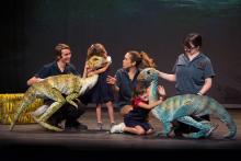During a production of "Erth's dinos zoo live" cast members and two children interact with two dinosaur puppets