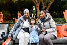 Boo at the Zoo. Family sitting on a bench with treat bags. 