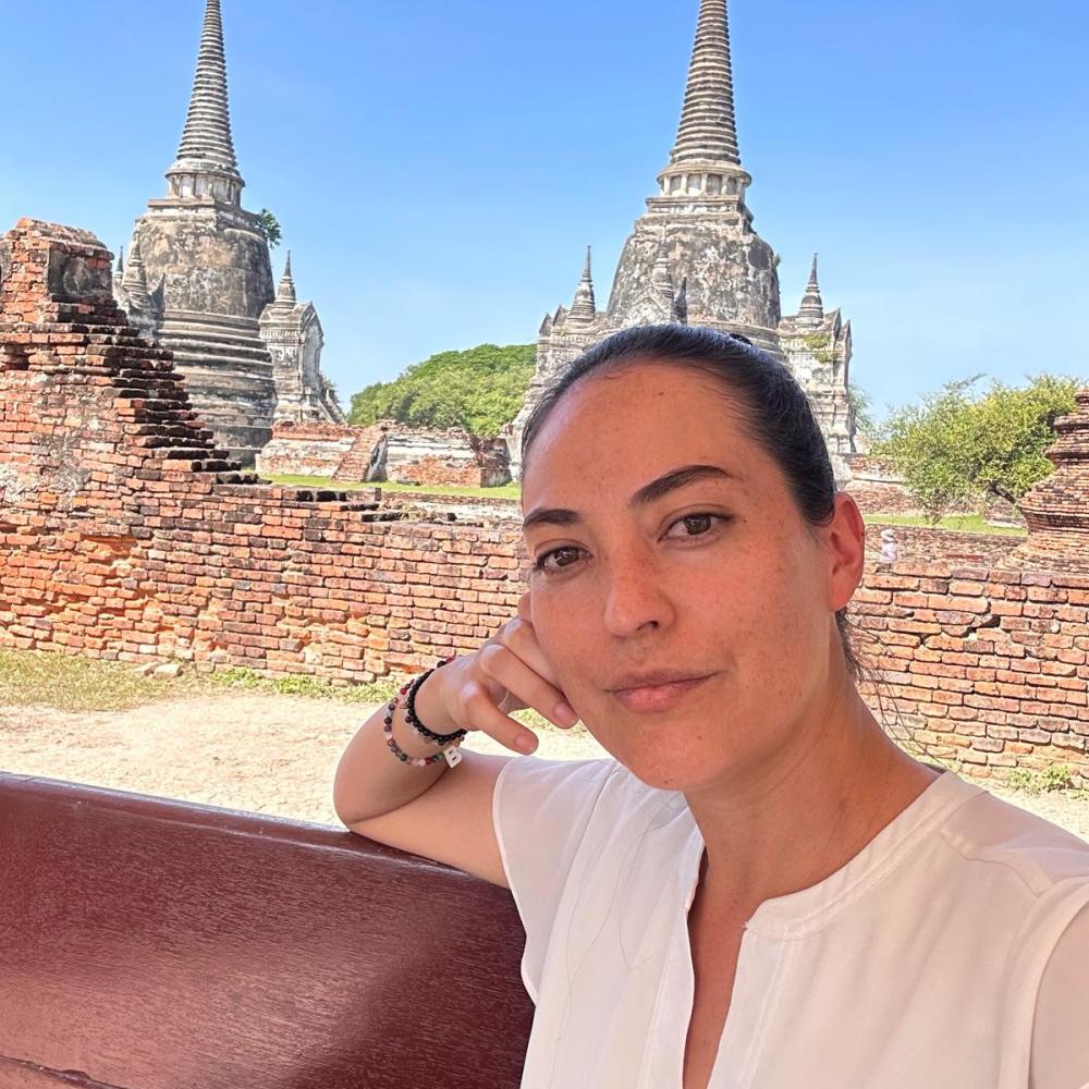 Headshot of a dark-haired woman in front of an ancient temple building.