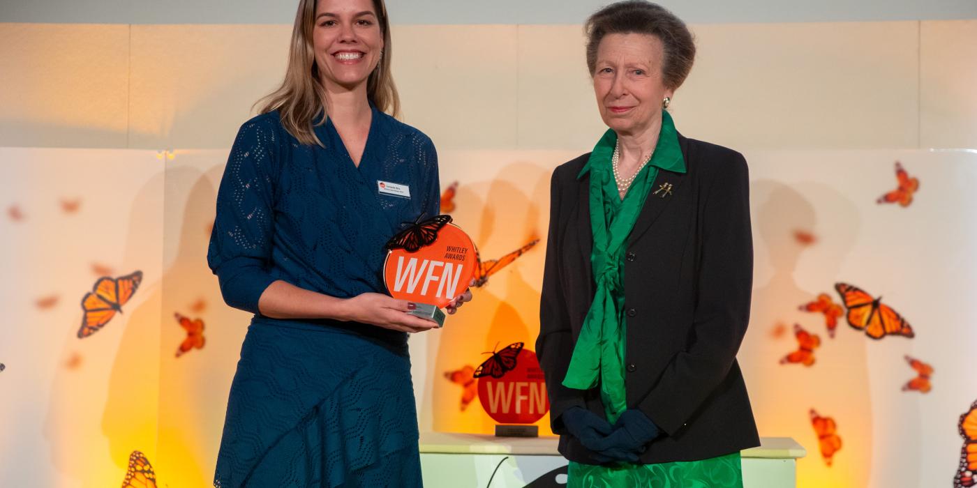 Photo of Smithsonian scientist Fernanda Abra smiling and holding an award. Beside her stands British royal Princess Anne, who presented her with the award.