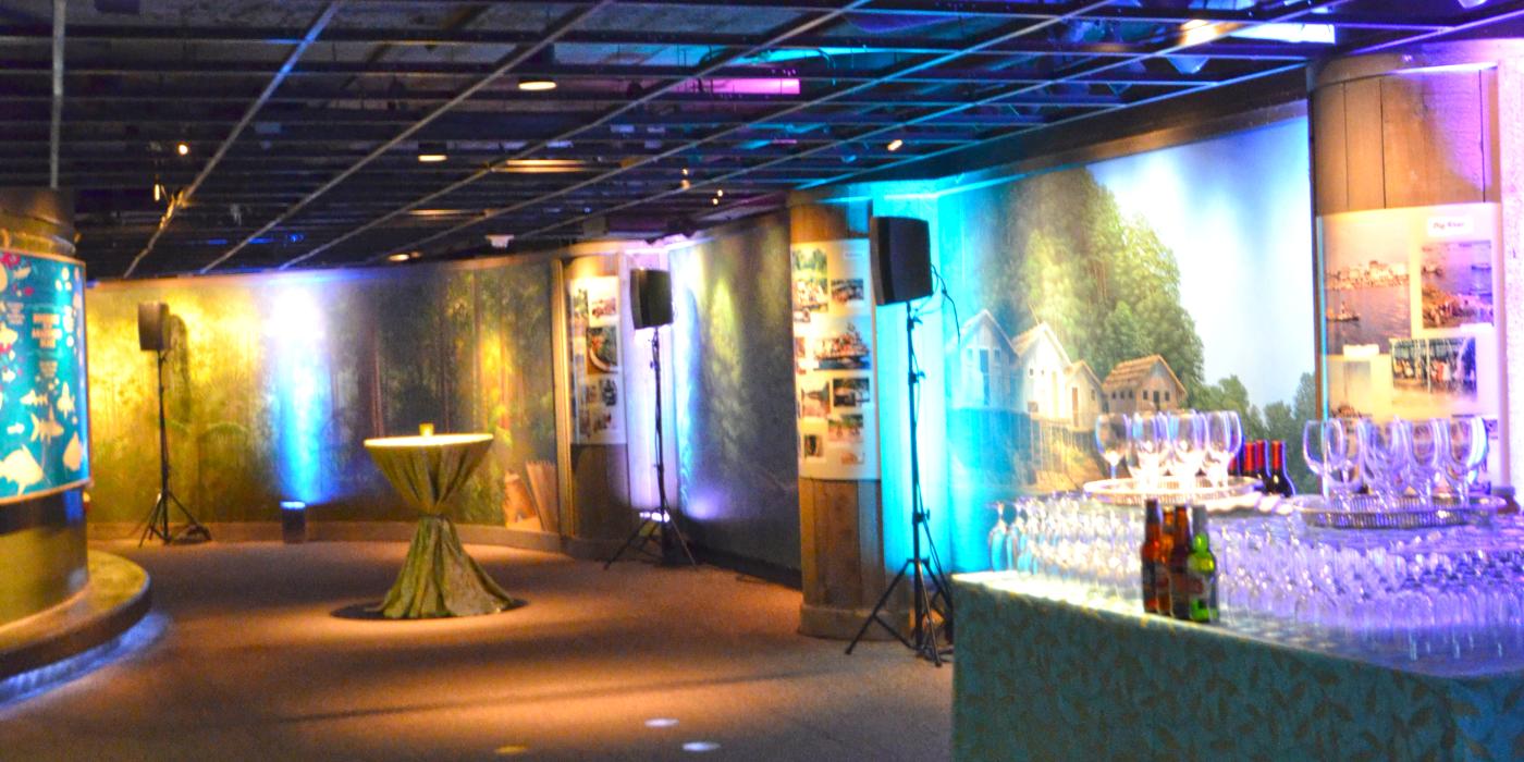 A catered event with a table stacked with wine glasses and cocktail tables set up in the Smithsonian's National Zoo's Amazonia exhibit