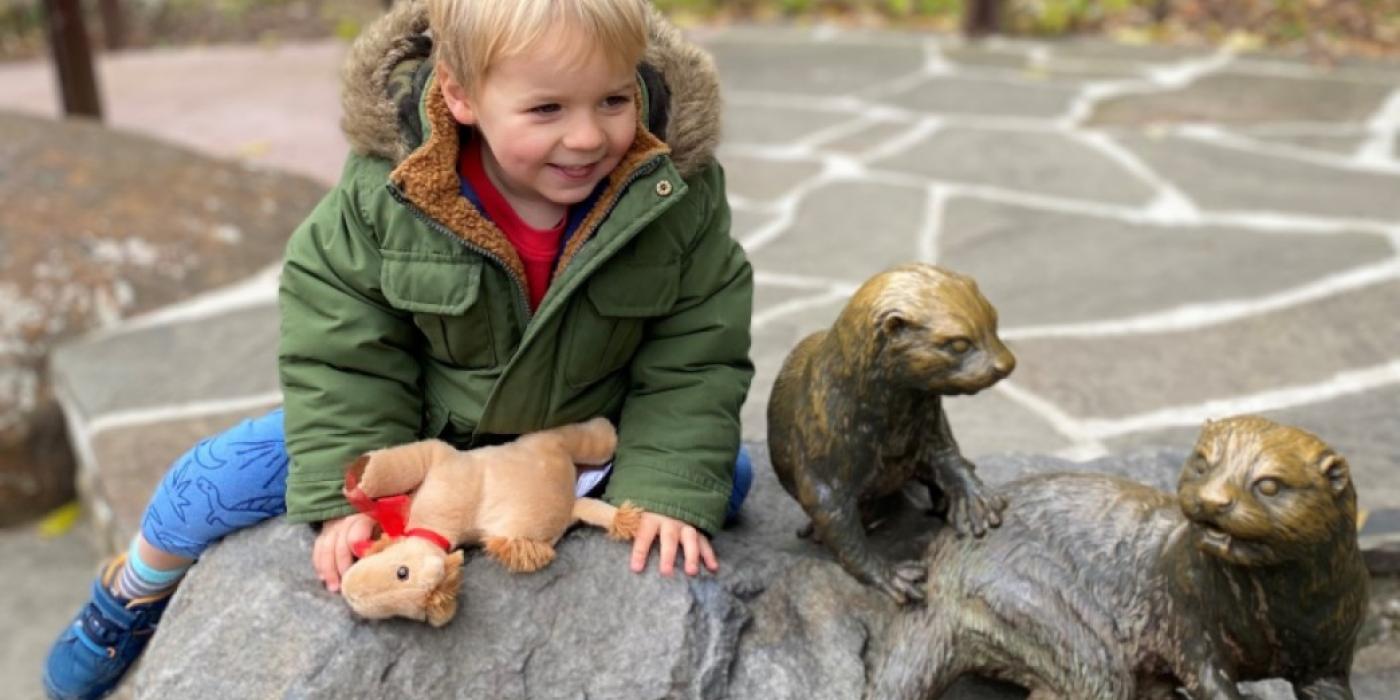 Child plays on Asian small clawed otter statue
