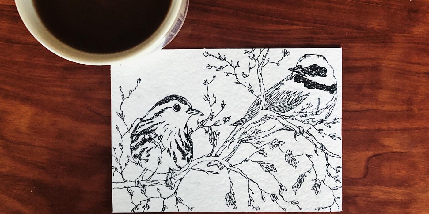 A mug of coffee placed next to a pen and ink drawing of two migratory birds perched on a tree branch